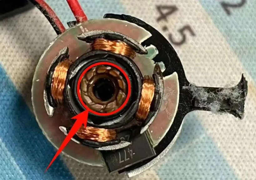 Dismantled industrial cabinet cooling fan showing severe sleeve bearing oil leakage and mechanical failure